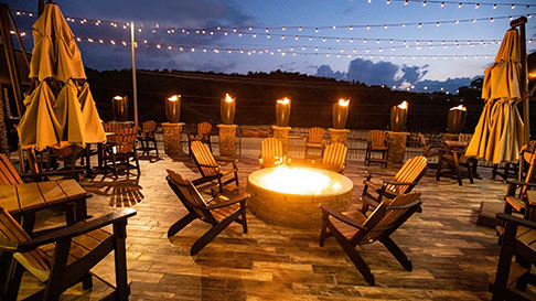 outside patio with fire pit, lounge chairs and tables and string lights